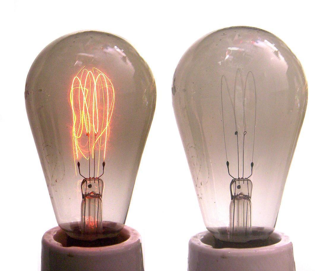 Figure 5 — 5 — Early carbon-filament lamps in operation. Their visible filament structure and low, warm output are the period lighting motif the aesthetic borrows — and their dimness is the feature, …