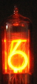 Figure 3 — 4 — A nixie tube at close range, the numeral cathode surrounded by its neon glow. The display is a visible mechanism rather than a screen: the stacked numerals, the wire anode mesh, and th…